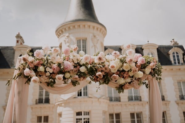 Arche fleurie devant un château pour mariage élégant